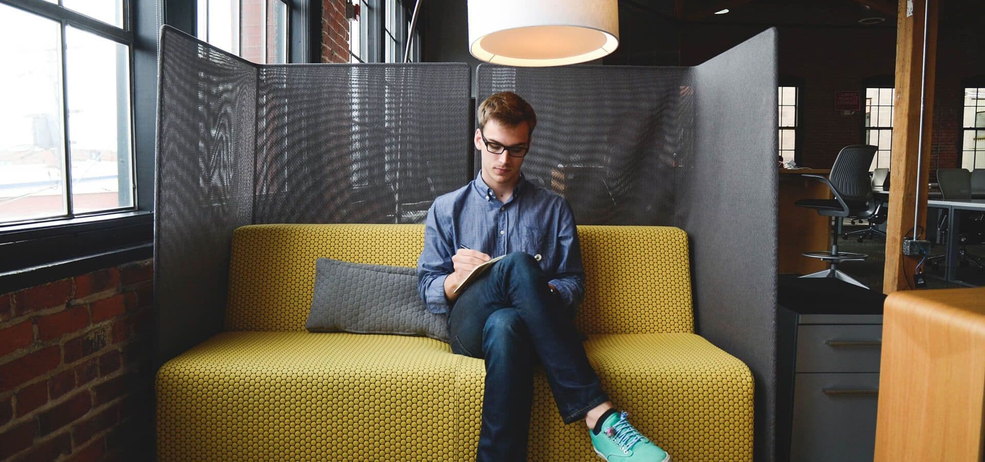 Chico trabajando con su tablet en un sofá de la oficina
